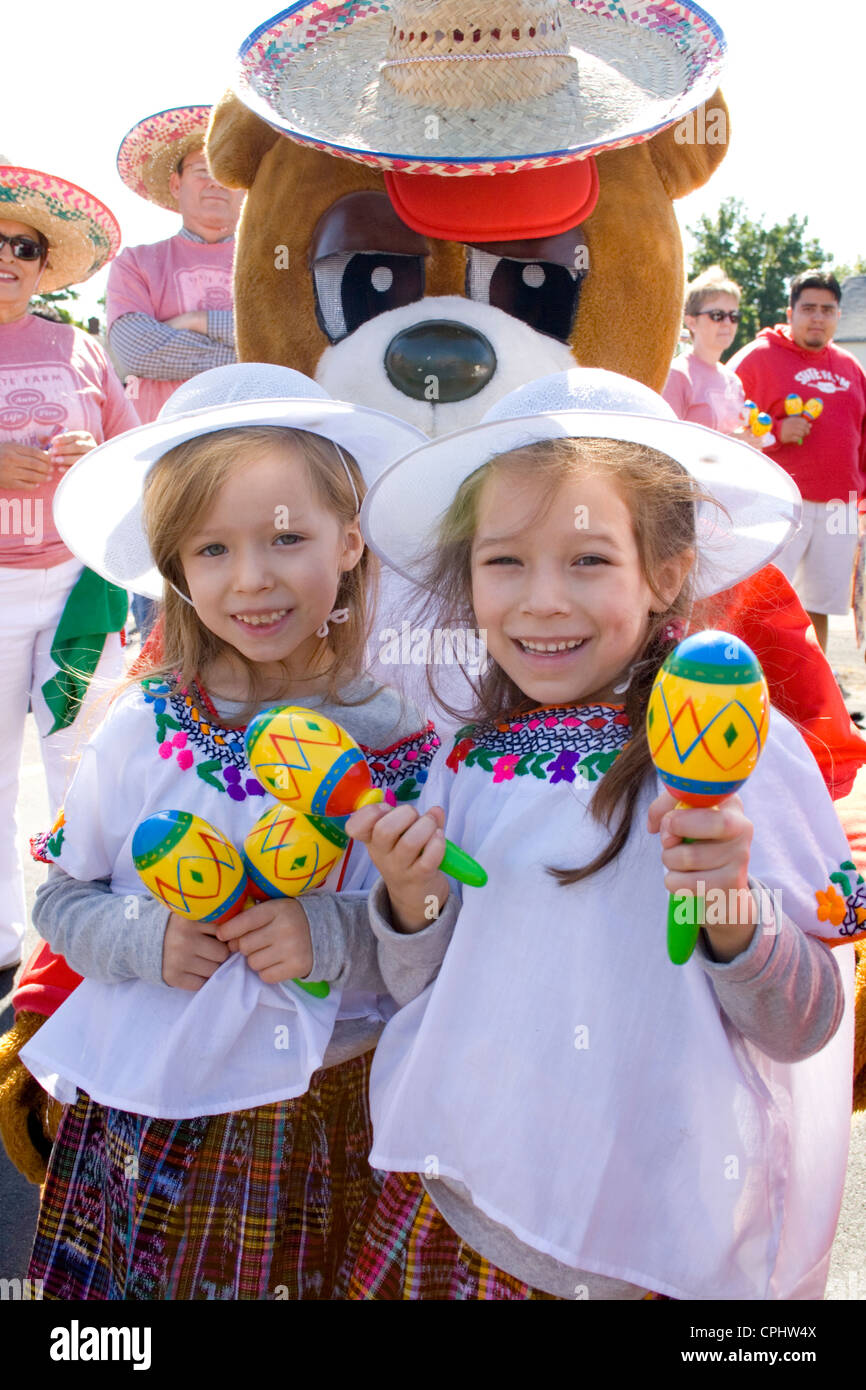 Felice di ragazze giovani agitando le maracas con orso mascotte in parata. Il giorno dell indipendenza messicana Minneapolis Minnesota MN USA Foto Stock