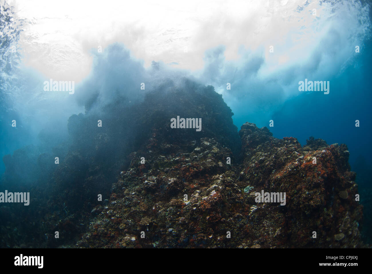 Il rigonfiamento si infrangono sulla cima di una scogliera affiorante nell Est dell isola di Lembeh in Indonesia. Foto Stock