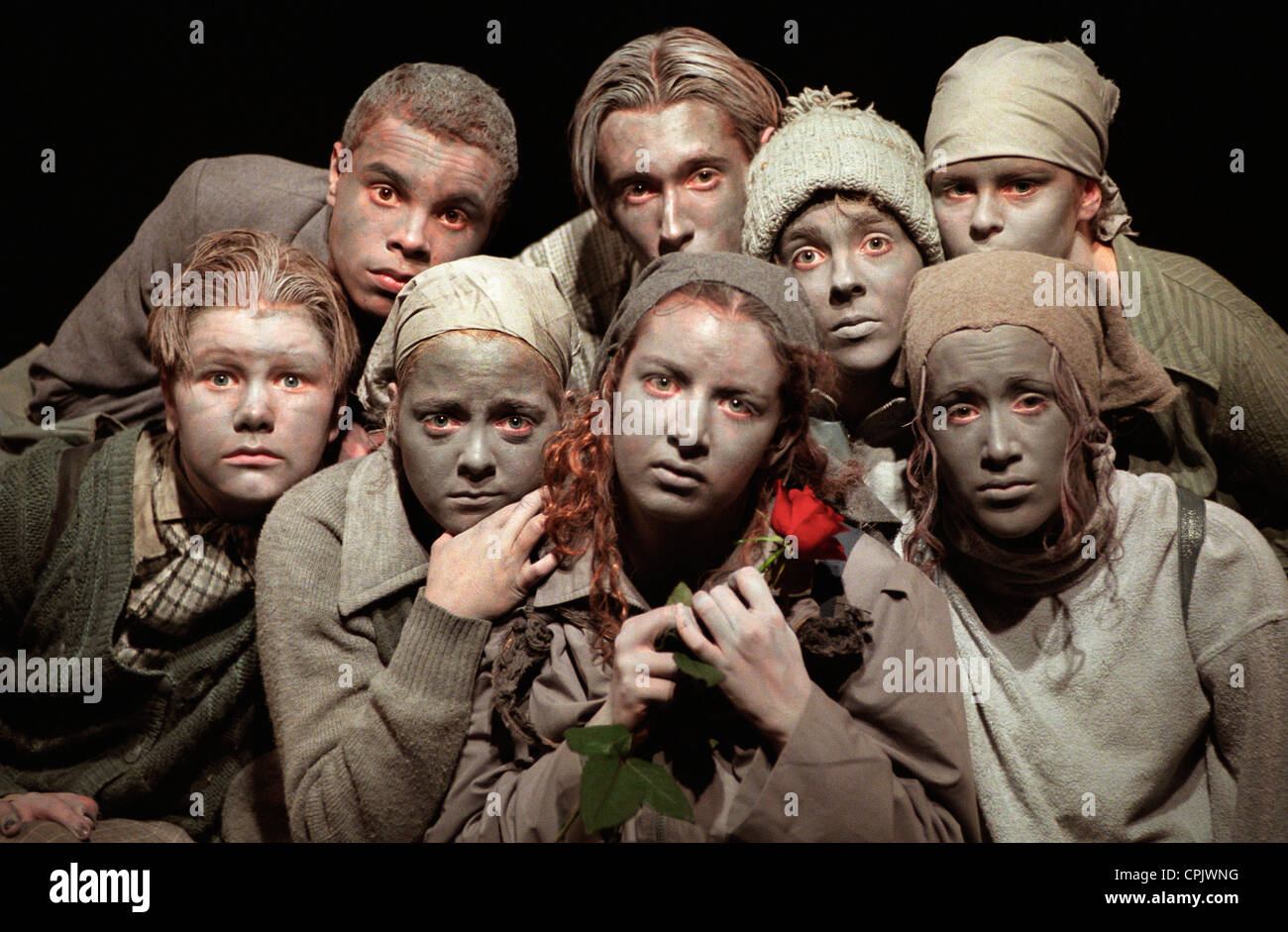 Un gruppo di giovani attori con colorate in grigio fanno eseguire ' Gray persone ' con una singola rosa rossa Foto Stock