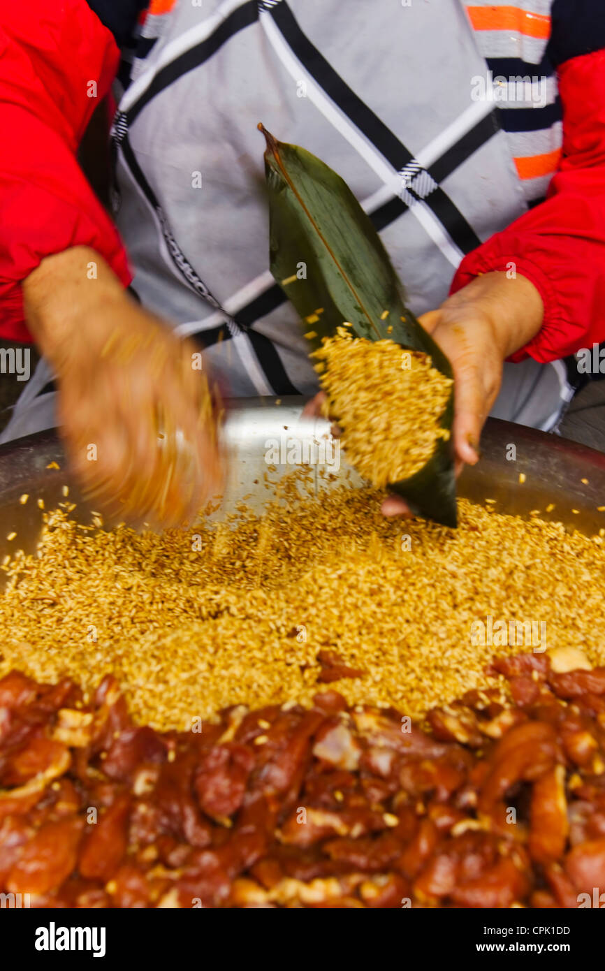 Donna fare Zongzi, cibo cinese fatta di riso glutinoso con diversi ripieni e avvolti in foglie di palma, Shanghai, Cina Foto Stock