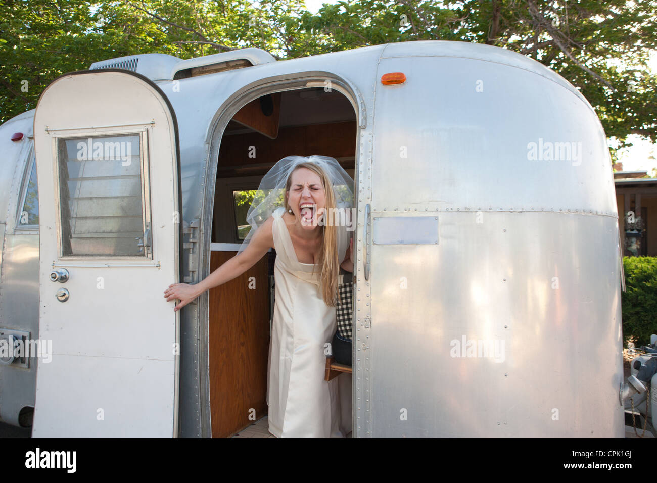 Sposa urlando con entusiasmo all'interno di un rimorchio Airstream. Foto Stock