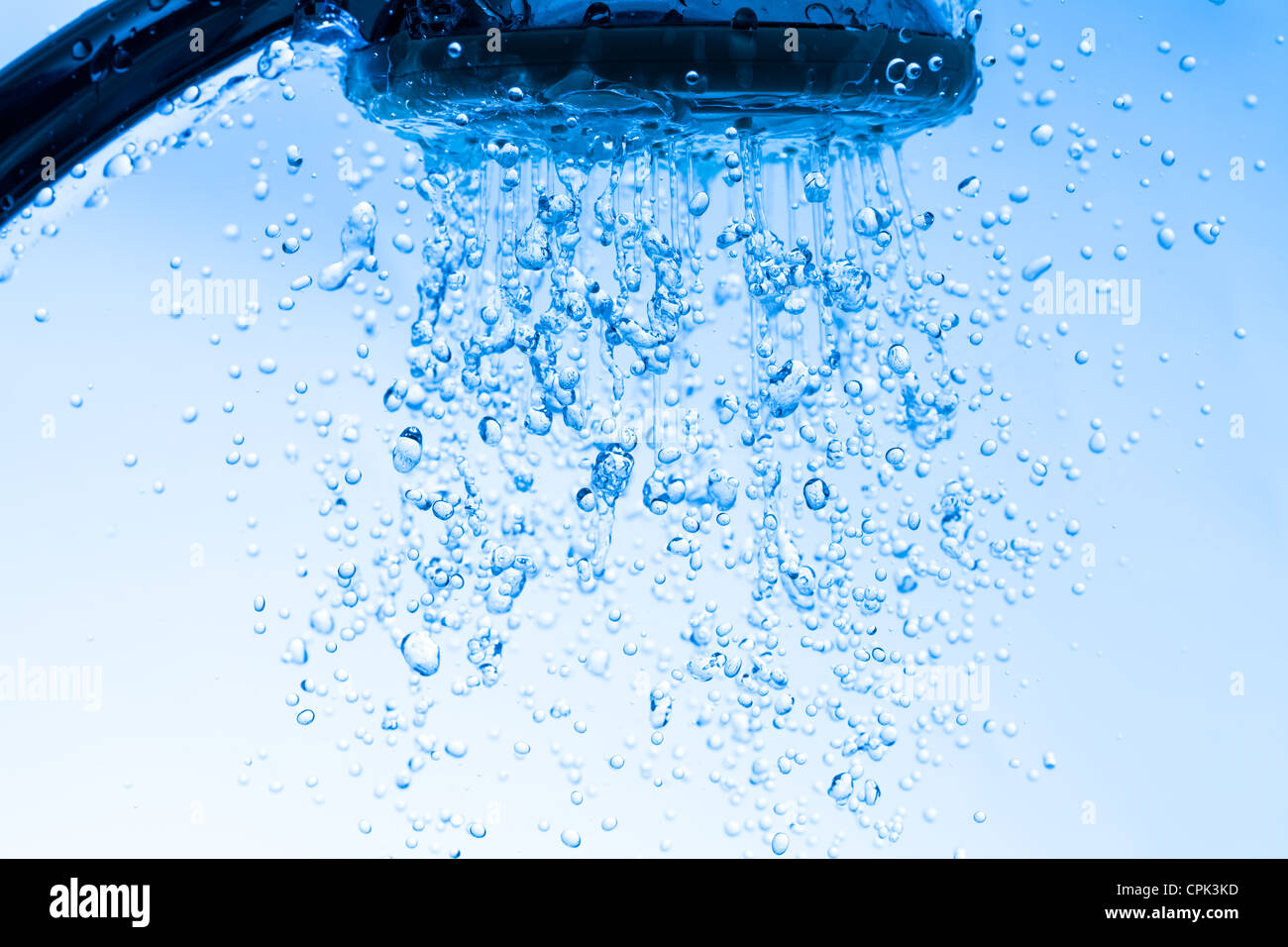 Testa di doccia con acqua corrente, sfondo blu Foto Stock