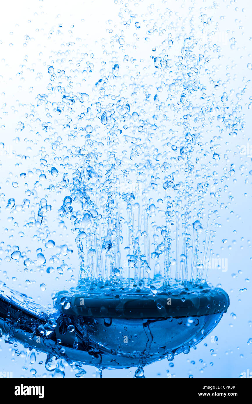 Testa di doccia con acqua corrente, sfondo blu Foto Stock