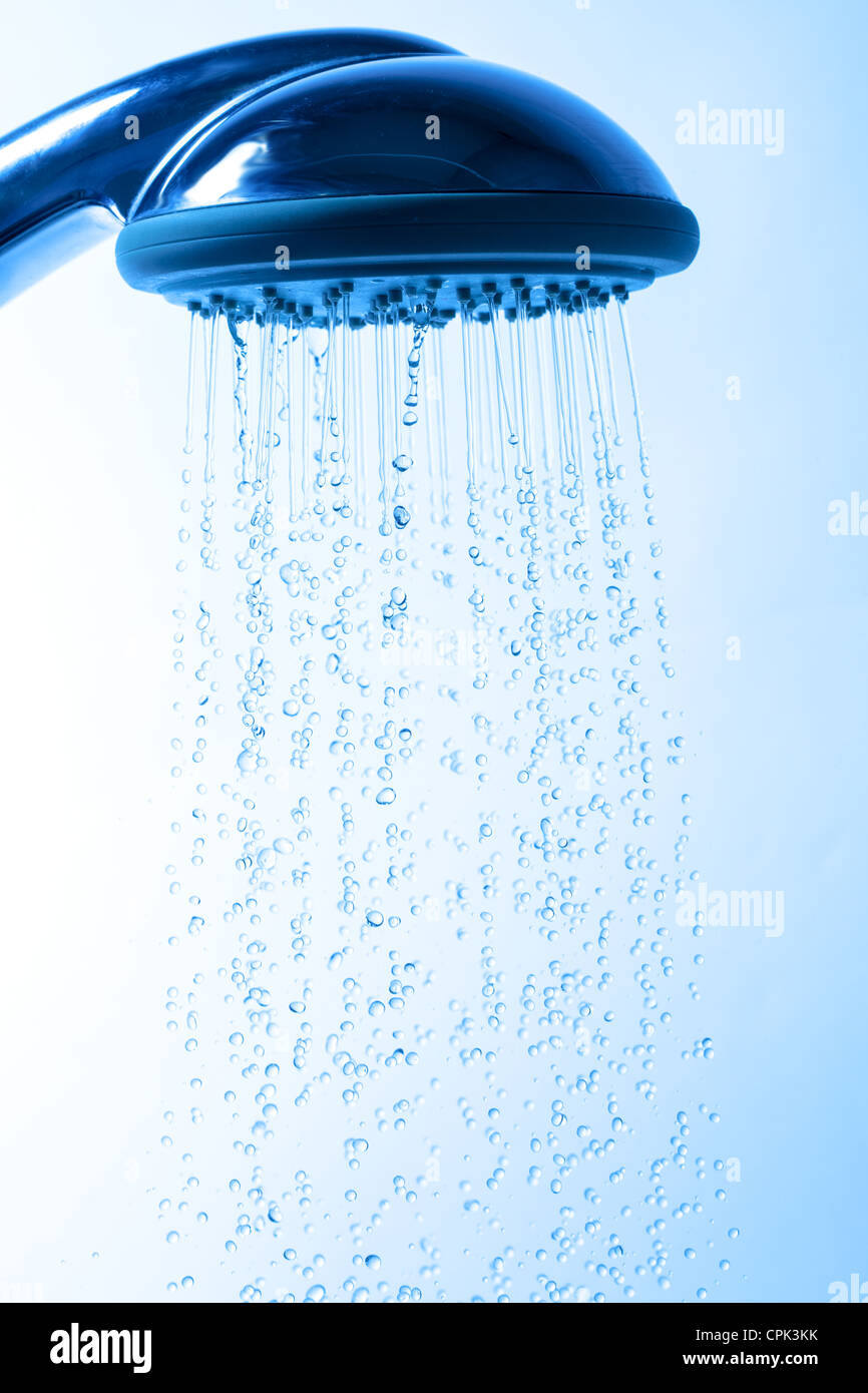 Testa di doccia con acqua corrente, sfondo blu Foto Stock