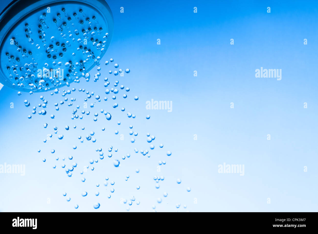 Testa di doccia con acqua di goccioline, sfondo blu Foto Stock