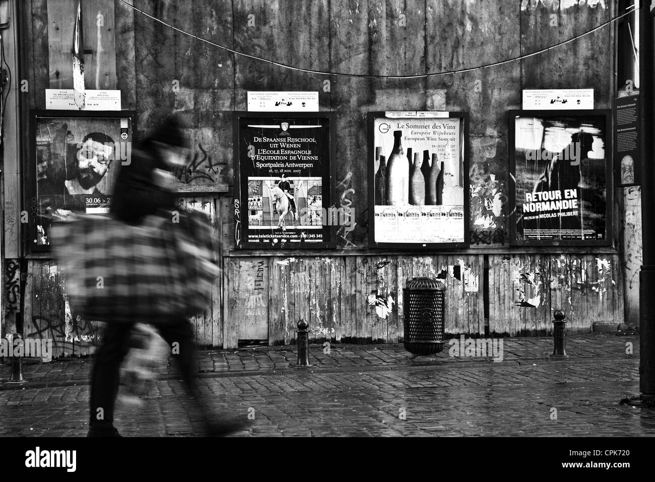 Scene di Bruxelles downtown, la gente che passa da una parete con la pubblicità. Girato a bassa velocità otturatore Foto Stock