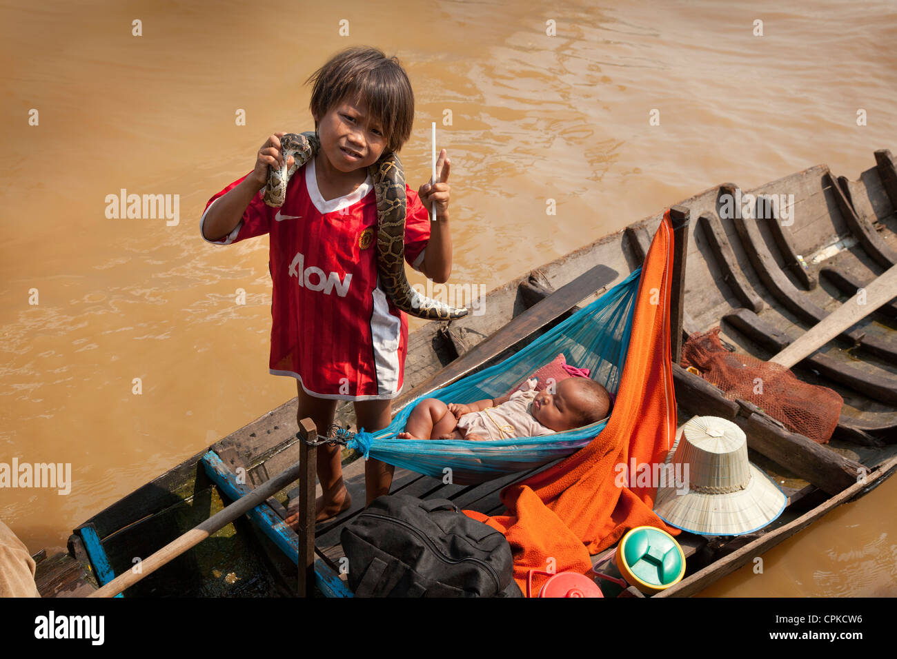 Lago Tonle Sap, Siem Reap, Cambogia. Boat people, bambino con snake mendica per due dollari, baby in amaca Foto Stock