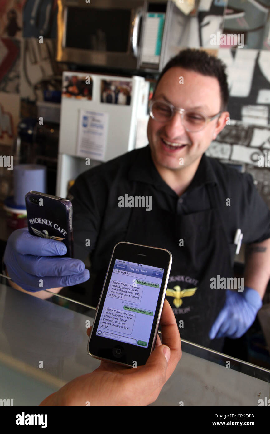 Acquisto di un elemento in un cafe da smart phone, un sistema che è in uso attraverso il Brixton Pound, una valuta alternativa. Foto Stock