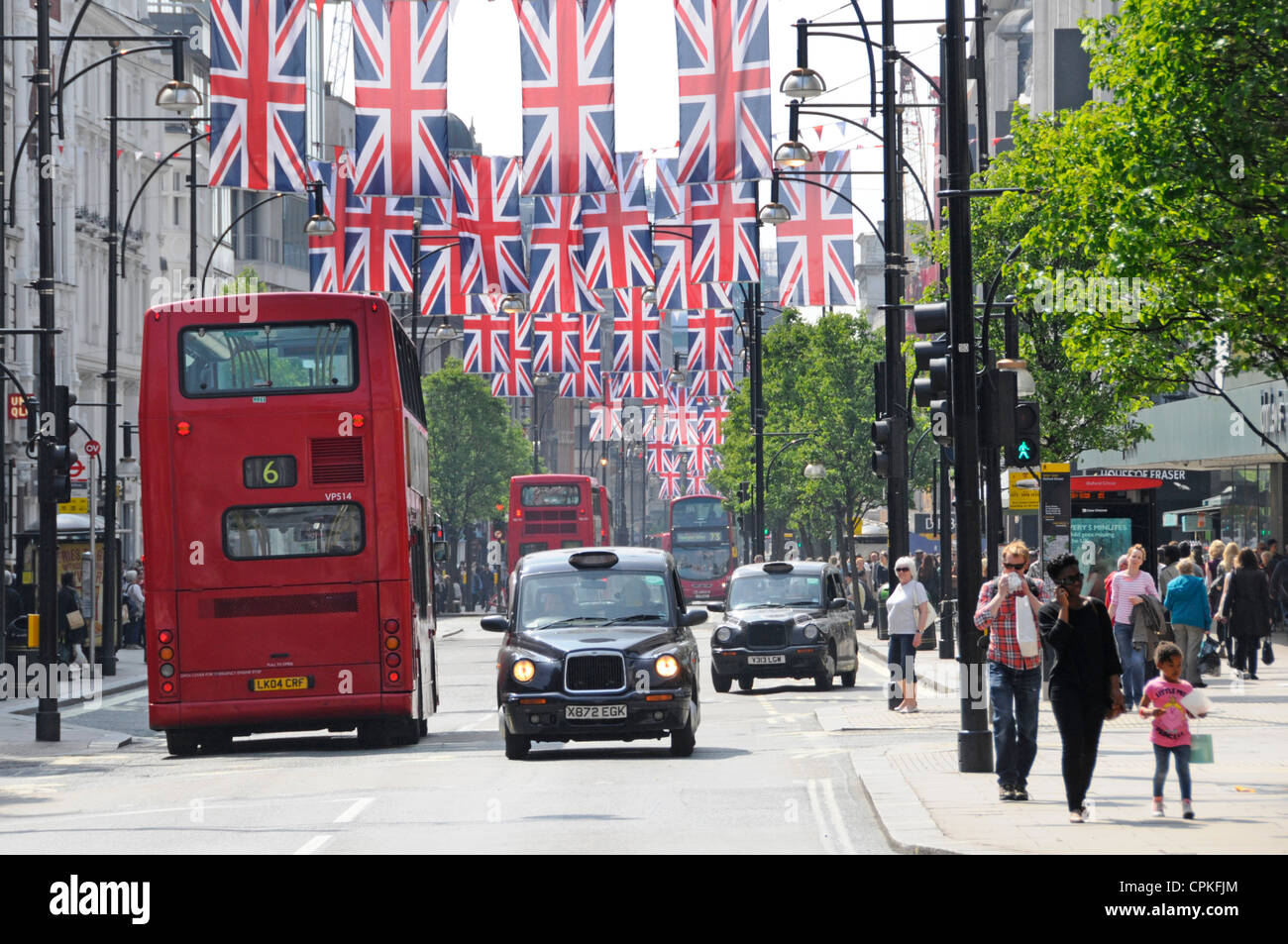 Shopping al dettaglio strada Red London autobus a due piani e taxi nero in scena Oxford Street con Jubilee & 2012 Olimpiadi Union Jack bandiere Inghilterra UK Foto Stock