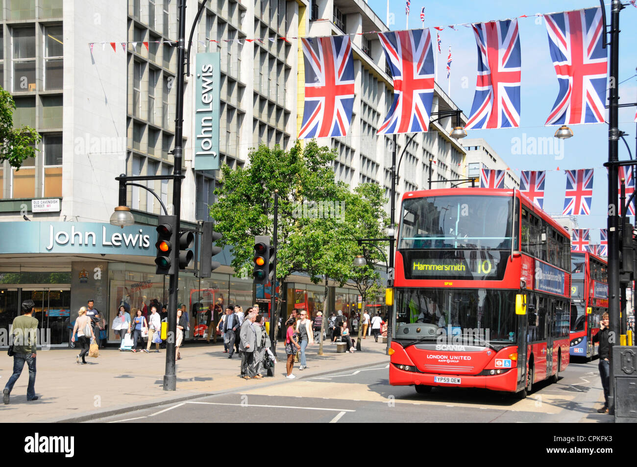 Autobus rossi al di fuori di John Lewis Store in Oxford Street con il giubileo Unione martinetti che possono anche essere nel luogo durante il 2012 Olimpiadi Foto Stock