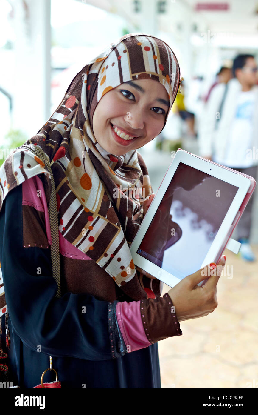 Ragazza musulmana che usa un iPad all'aperto. Foto Stock