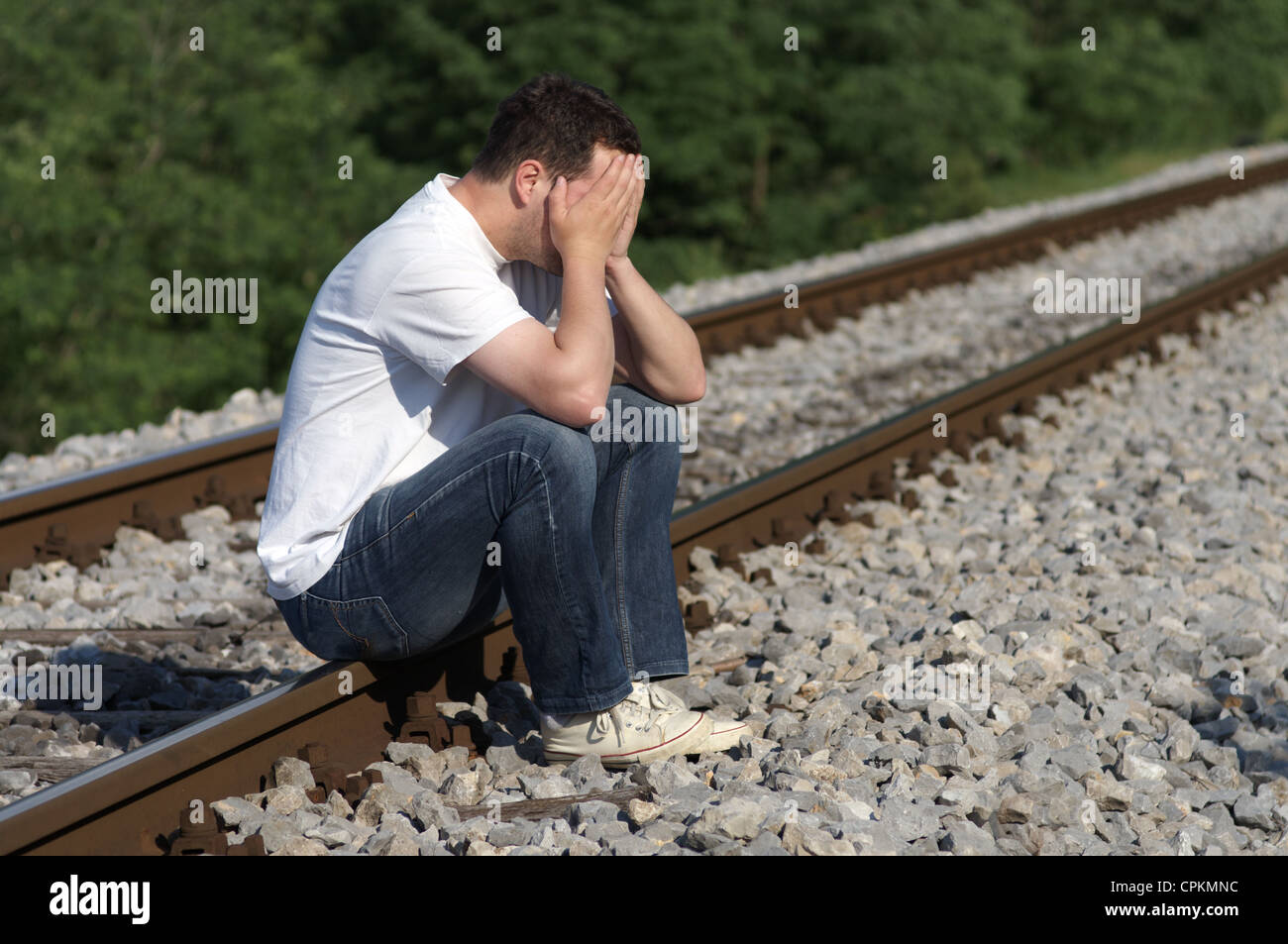 Uomo disperato che siede su binari ferroviari Foto Stock