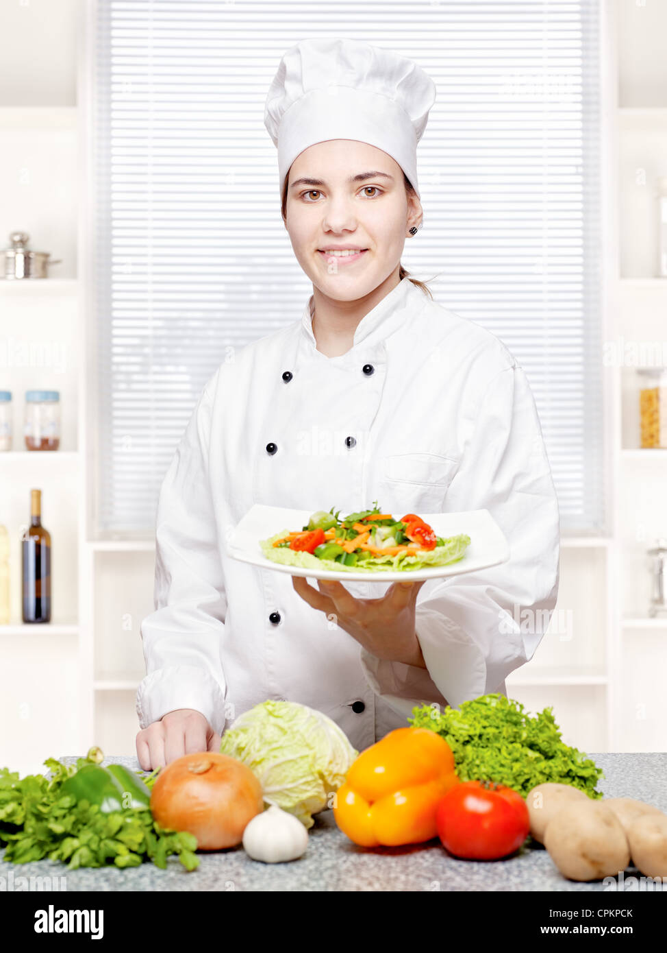 Il giovane chef che offre pasti vegetariani in cucina Foto Stock