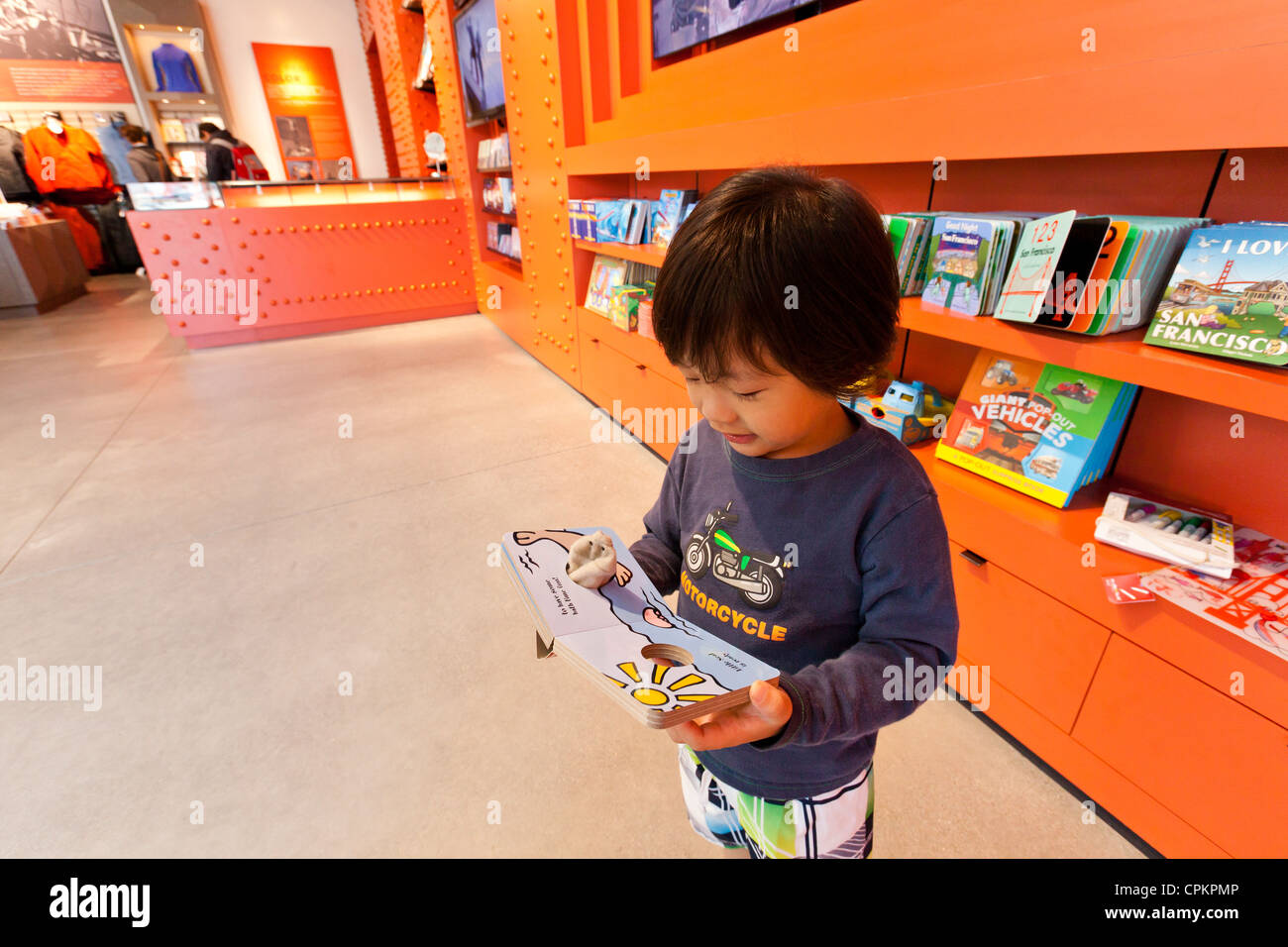 Un piccolo ragazzo asiatico la lettura di un libro per bambini in libreria Foto Stock