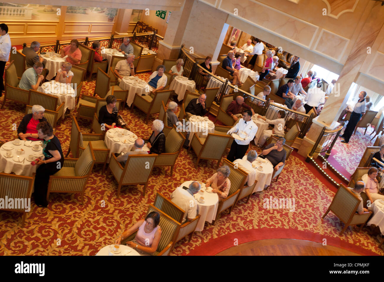 Steward che serve il tè del pomeriggio, panini, torte, focaccine con crema, a bordo di Cunard la regina Victoria Foto Stock