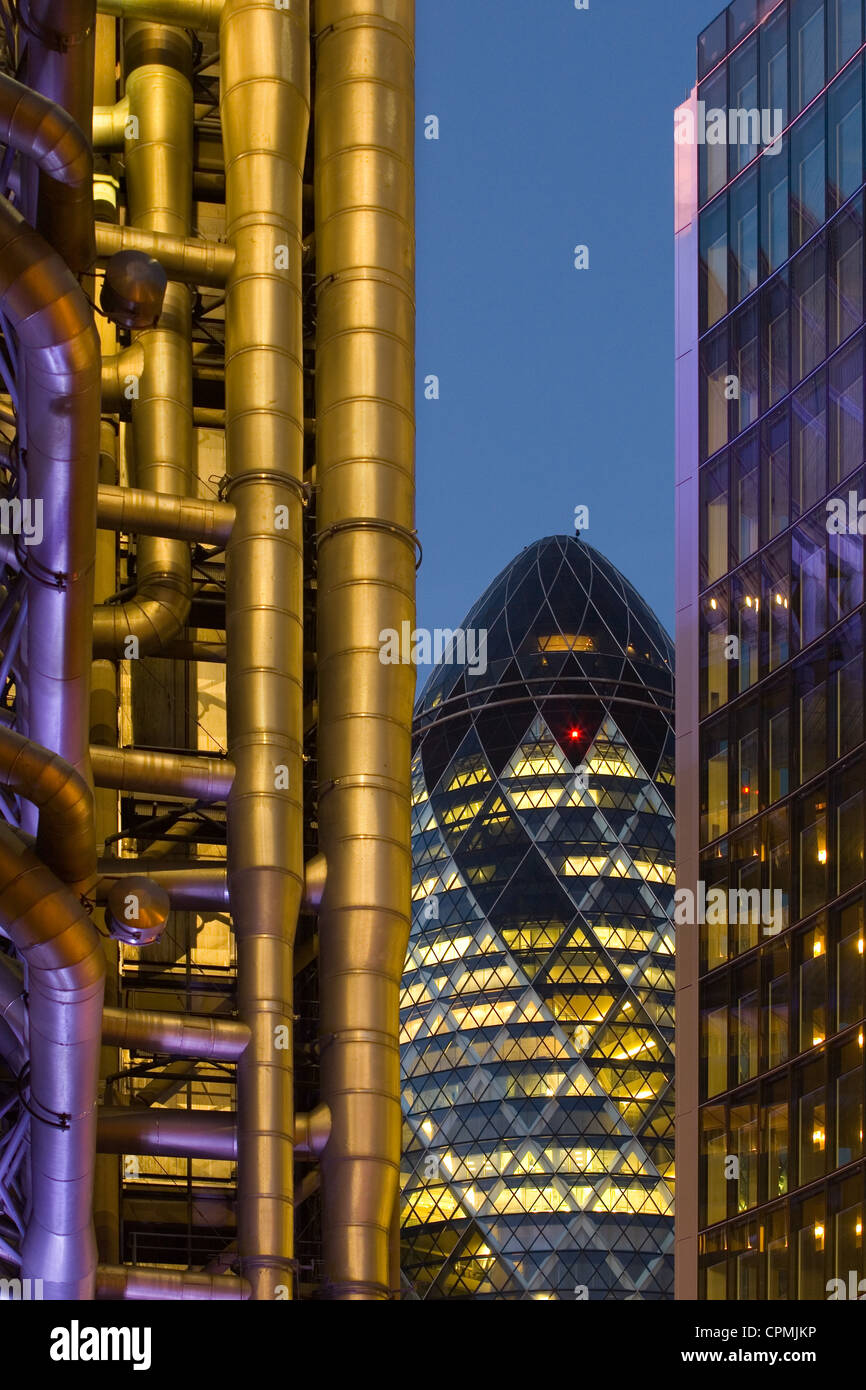 La Swiss Re Building - aka il Gherkin - di notte, messo in luce dalla Lloyds Building Foto Stock