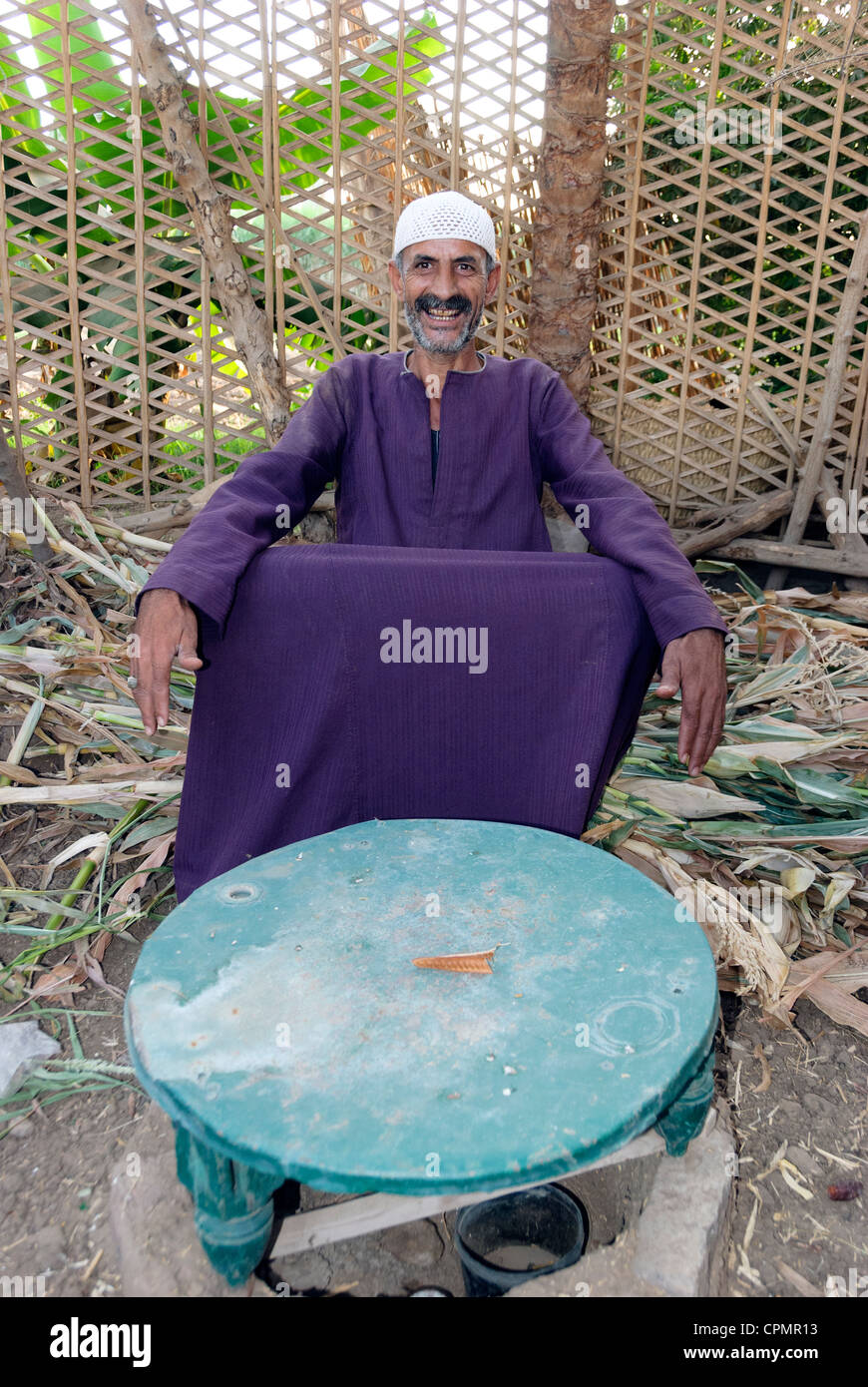 Egiziano sorridente uomo seduto a tavola - Villaggio di Esba, Tebe occidentale, Alto Egitto Foto Stock