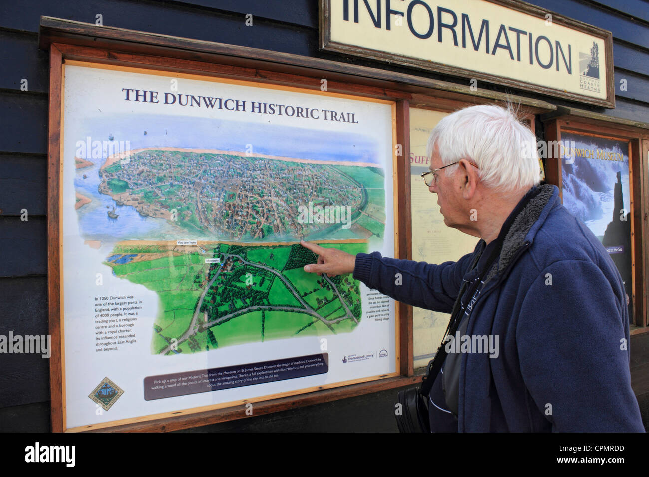 Uomo che guarda la mappa che mostra l'erosione costiera a Dunwich Inghilterra Suffolk REGNO UNITO Foto Stock