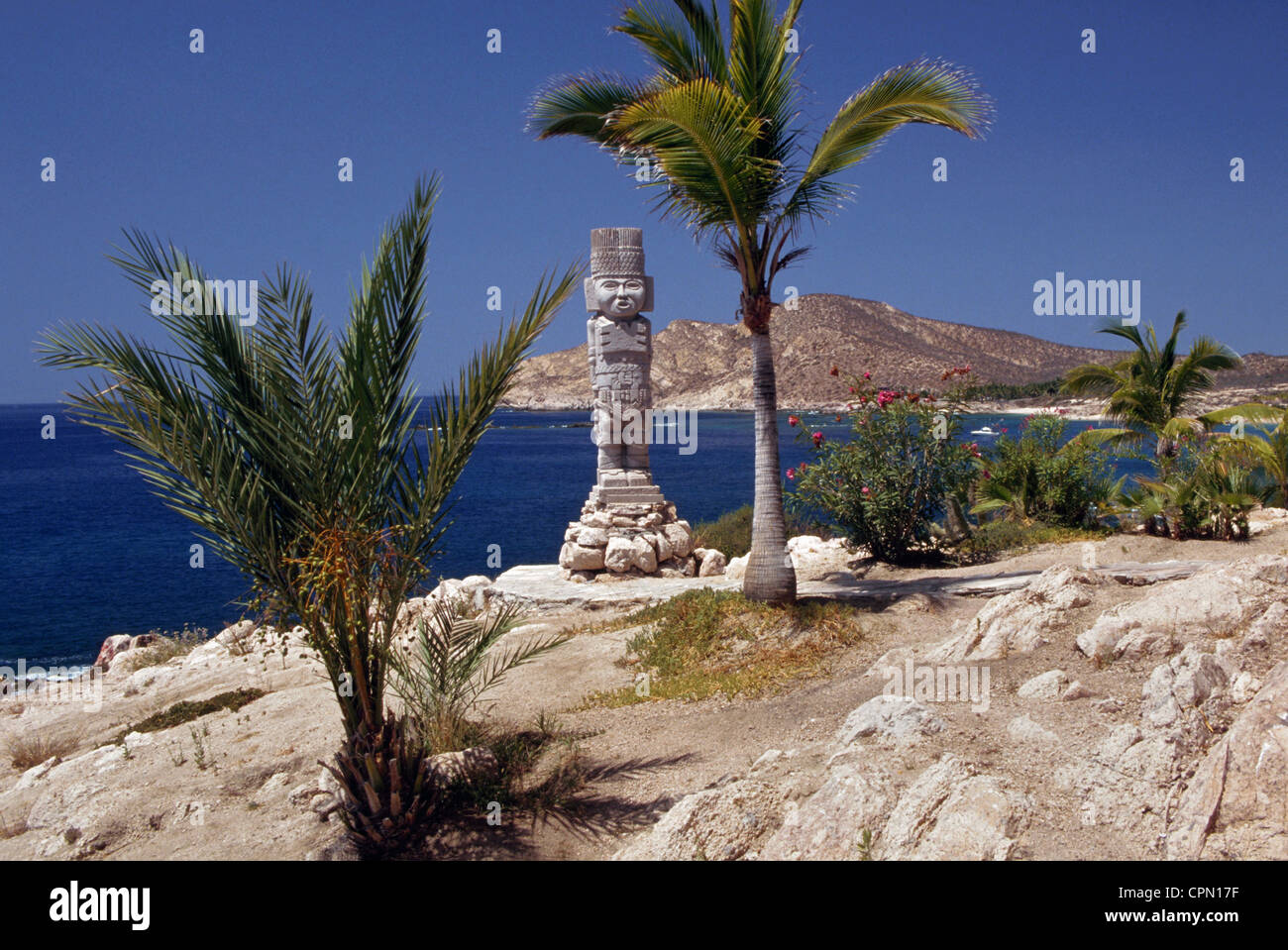 Un lone stone Aztec statua si trova in corrispondenza del bordo del mare di Cortez nel villaggio turistico città di Cabo San Lucas sulla penisola della Baja California in Messico. Foto Stock