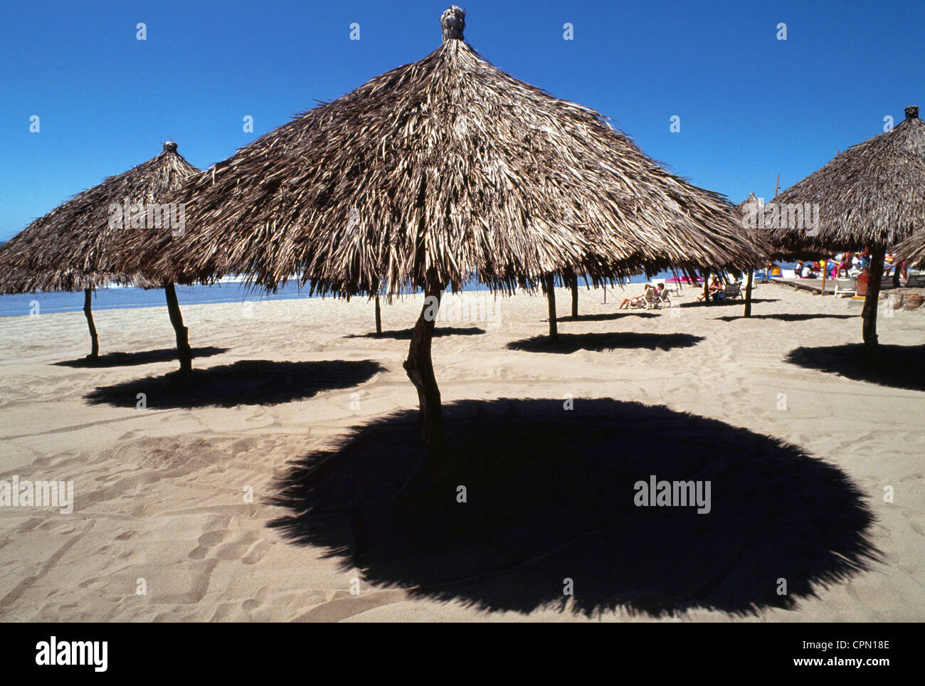 Con il tetto di paglia palapas offrono ombra a beachgoers che cercano sollievo dal sole tropicale a Puerto Vallarta Resort sulla Costa Pacifica del Messico. Foto Stock