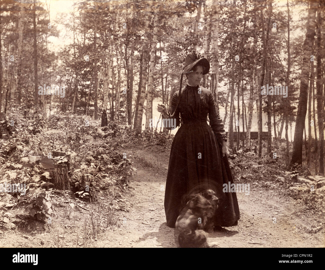 Donna vittoriana prendendo cane per una passeggiata nel bosco Foto Stock