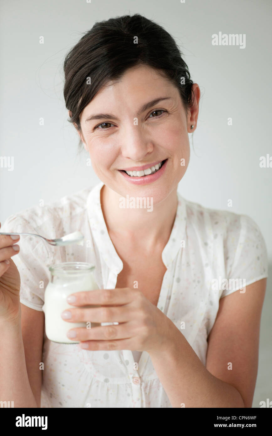 Metà donna adulta mangiare yogurt, ritratto Foto Stock