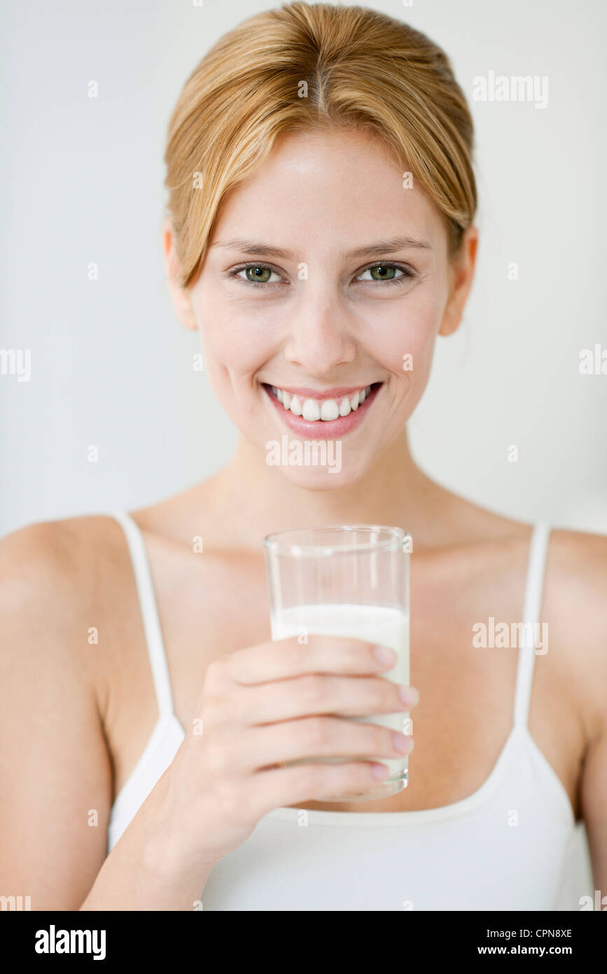 Giovane donna tenendo un bicchiere di latte, ritratto Foto Stock