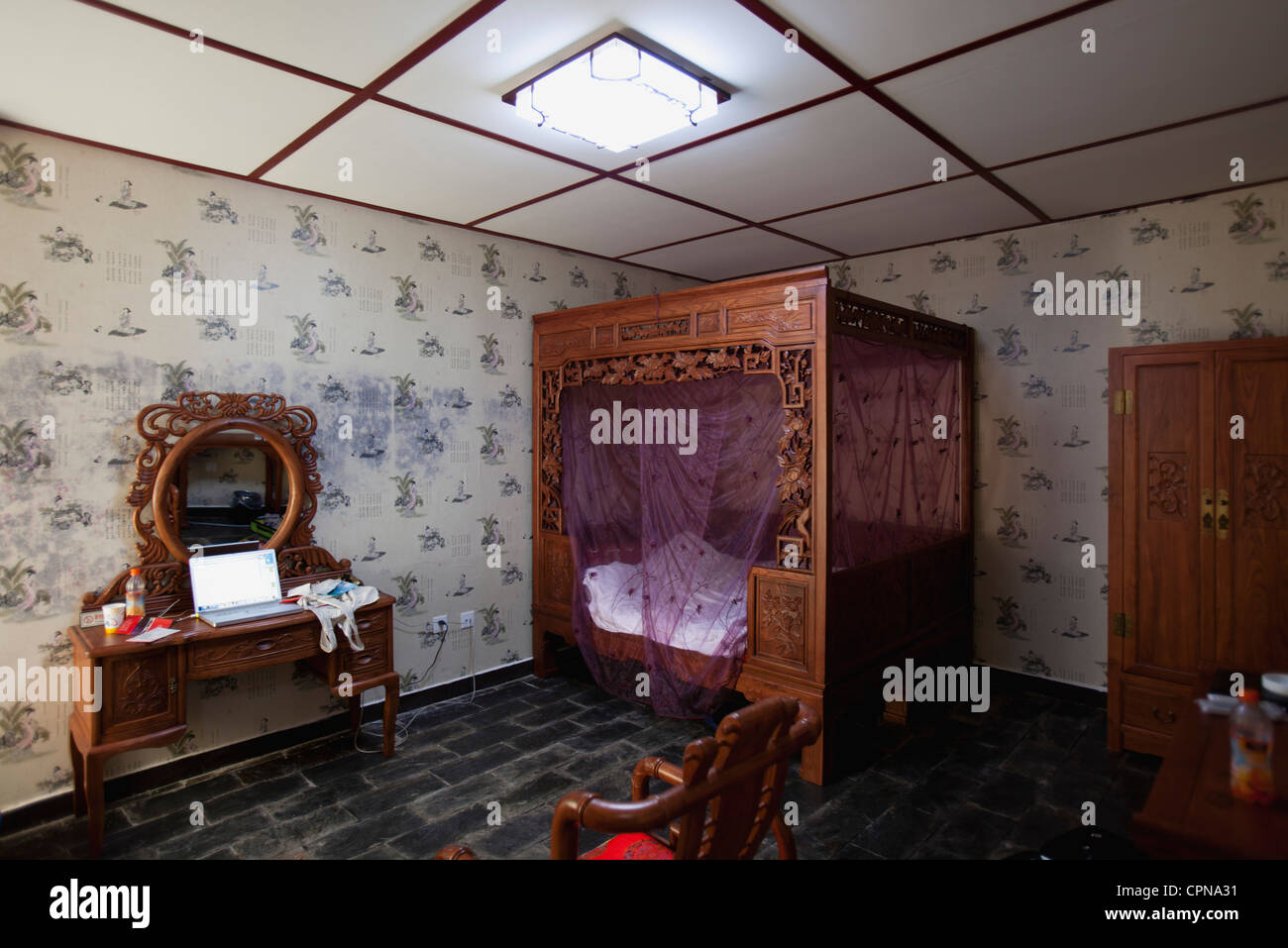 Camera da letto arredata con le spalliere mobili intagliati e letto a baldacchino Foto Stock