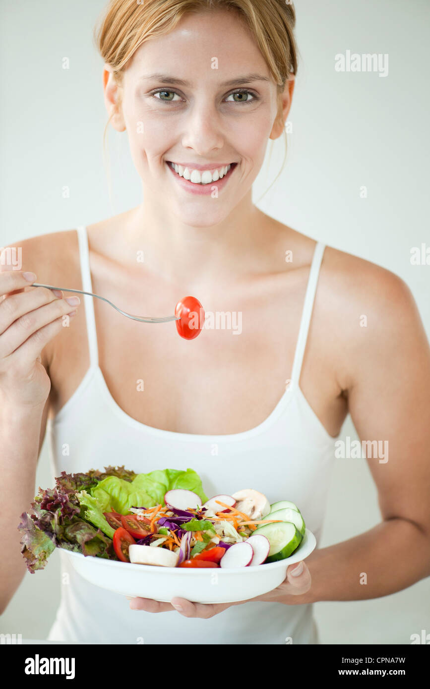 Giovane donna mangiare ciotola di insalata Foto Stock