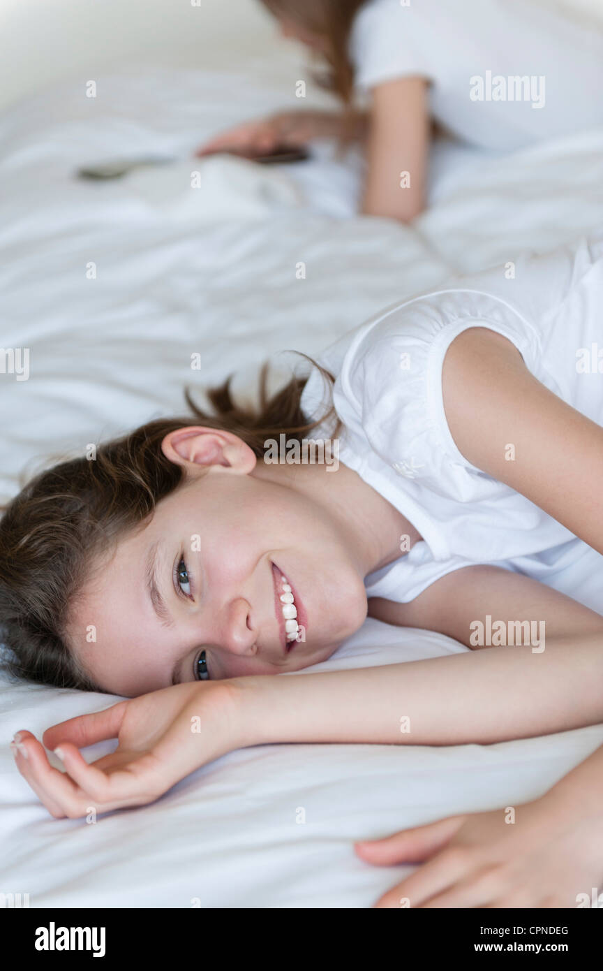 Ragazza distesa sul letto, sorridente Foto Stock