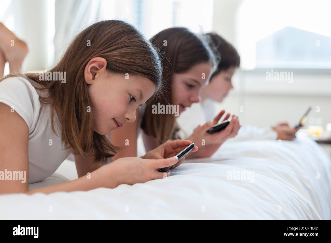 I fratelli giacente sul letto palmare riproduzione di video giochi Foto Stock