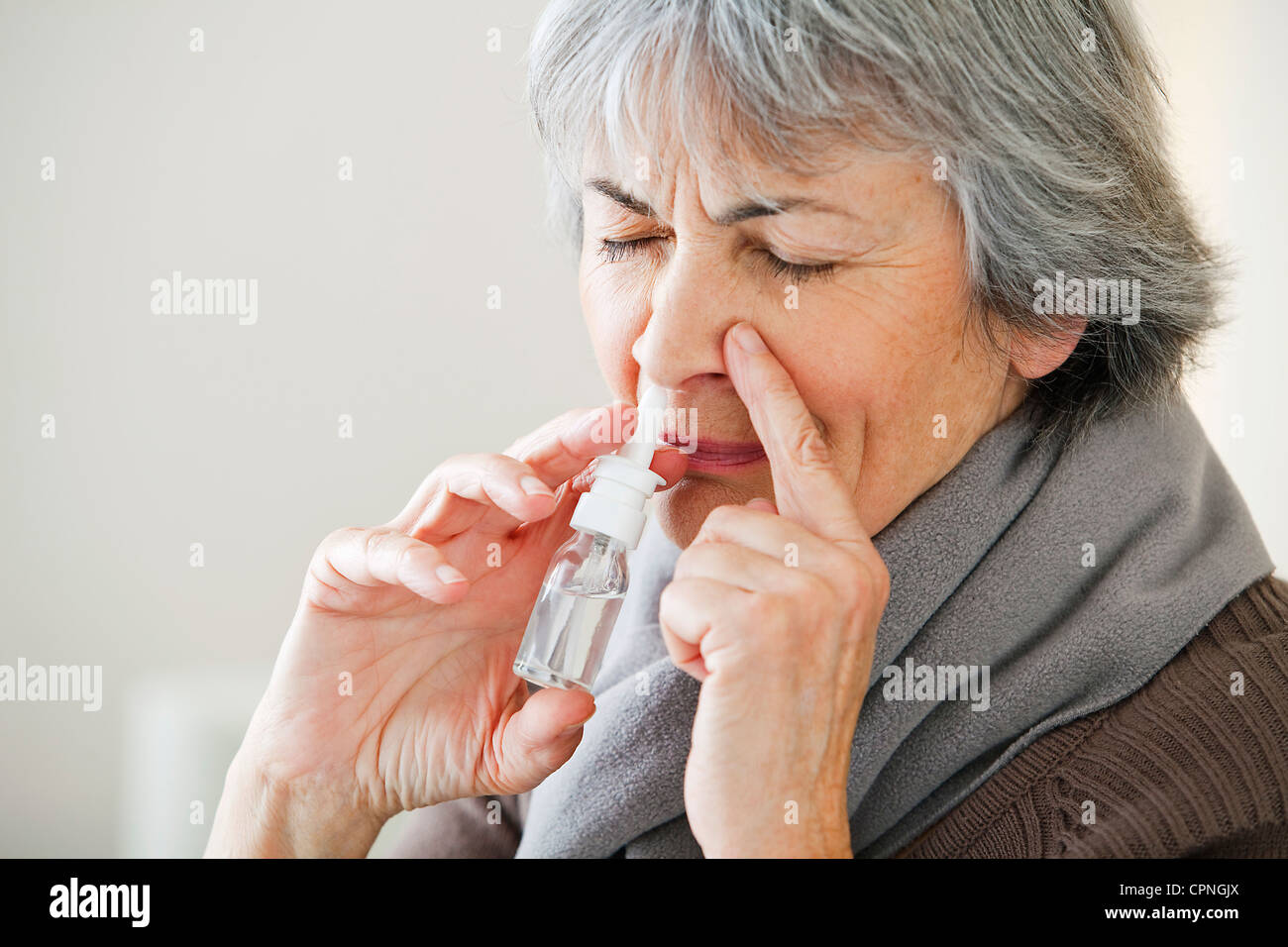 Persona anziana mediante spray nasale Foto Stock