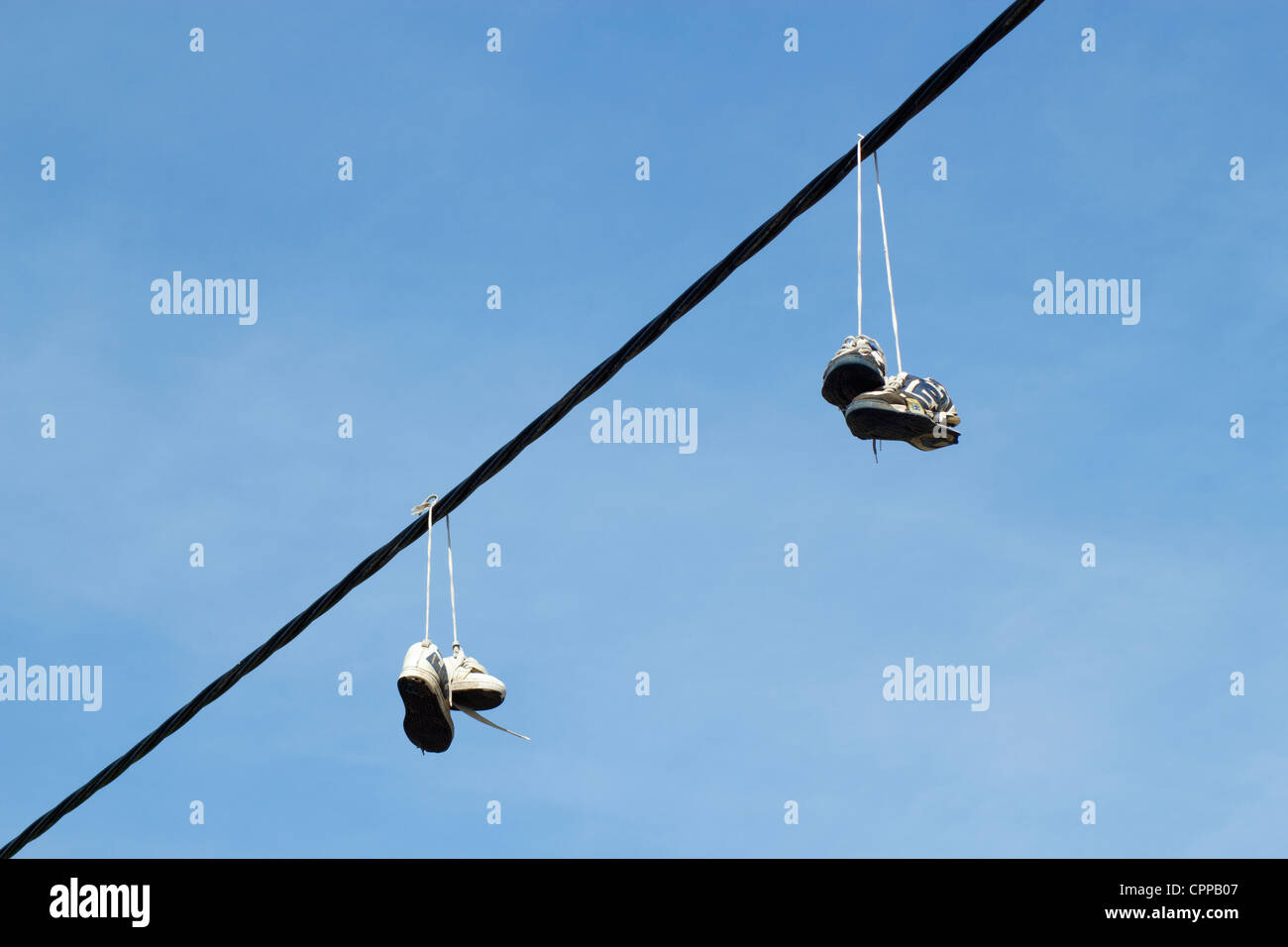 Due coppie di formatori scarpe running appesa a una linea telefonica. Foto Stock