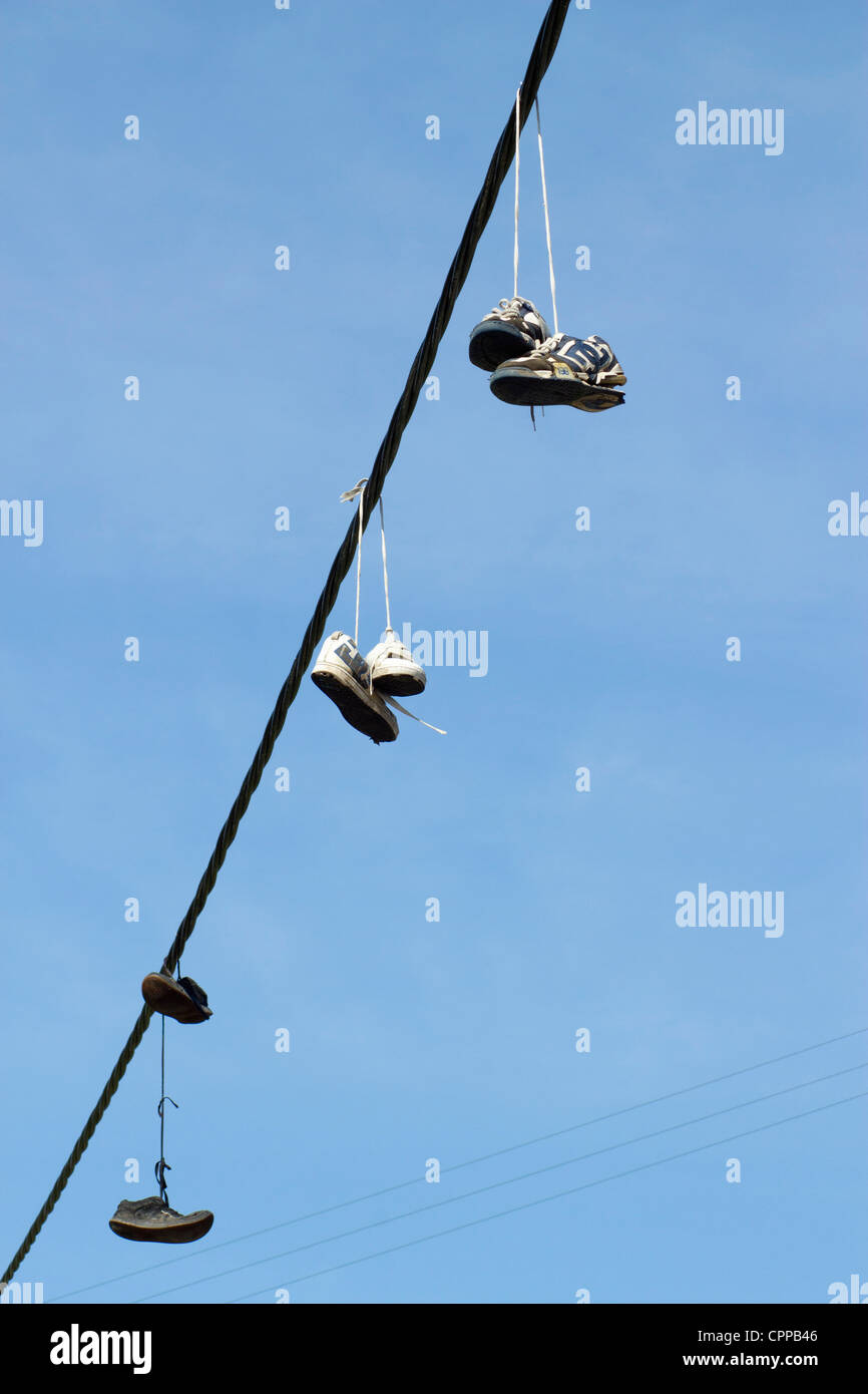 Tre coppie di formatori scarpe running appesa a una linea telefonica. Foto Stock