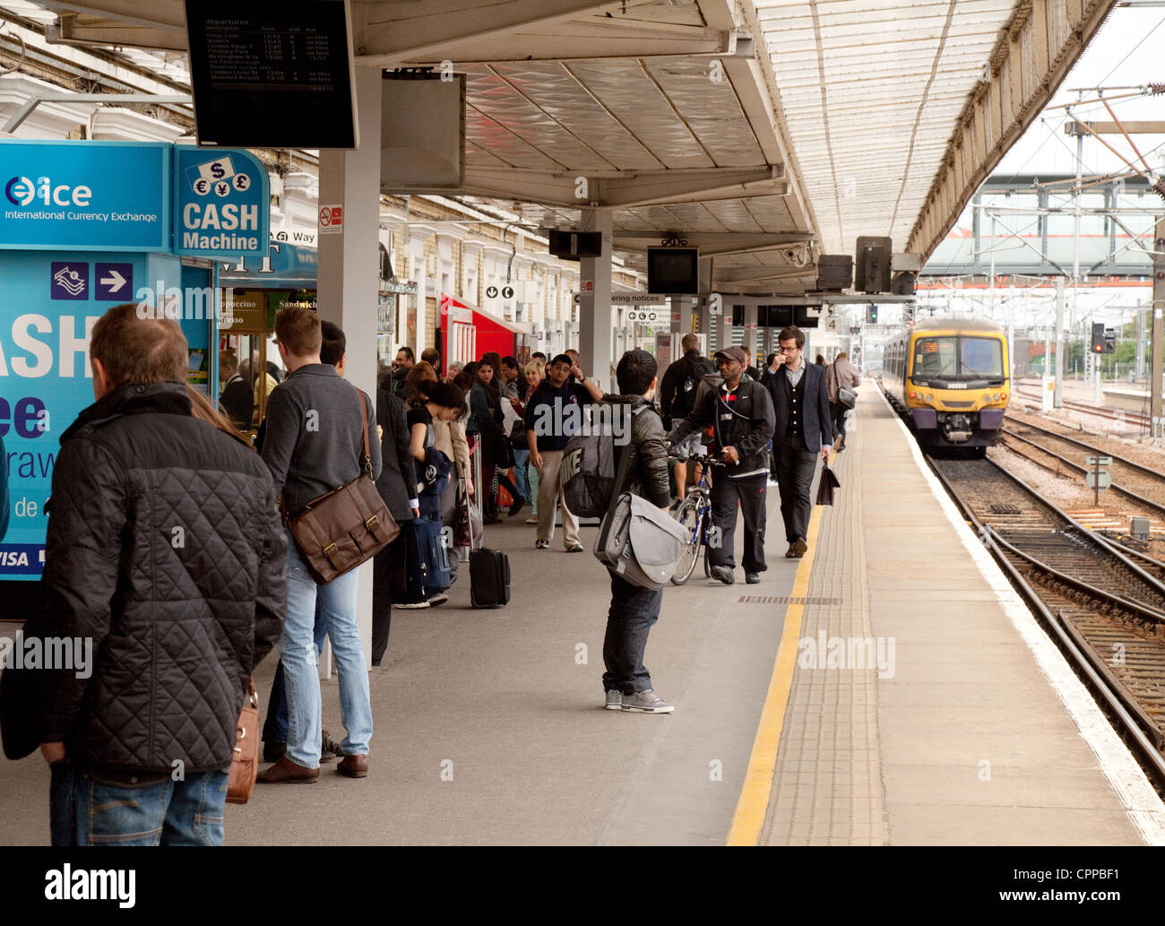 Chi viaggia in treno in attesa di un treno sul binario presso la stazione di Cambridge, Cambridgeshire Regno Unito Foto Stock