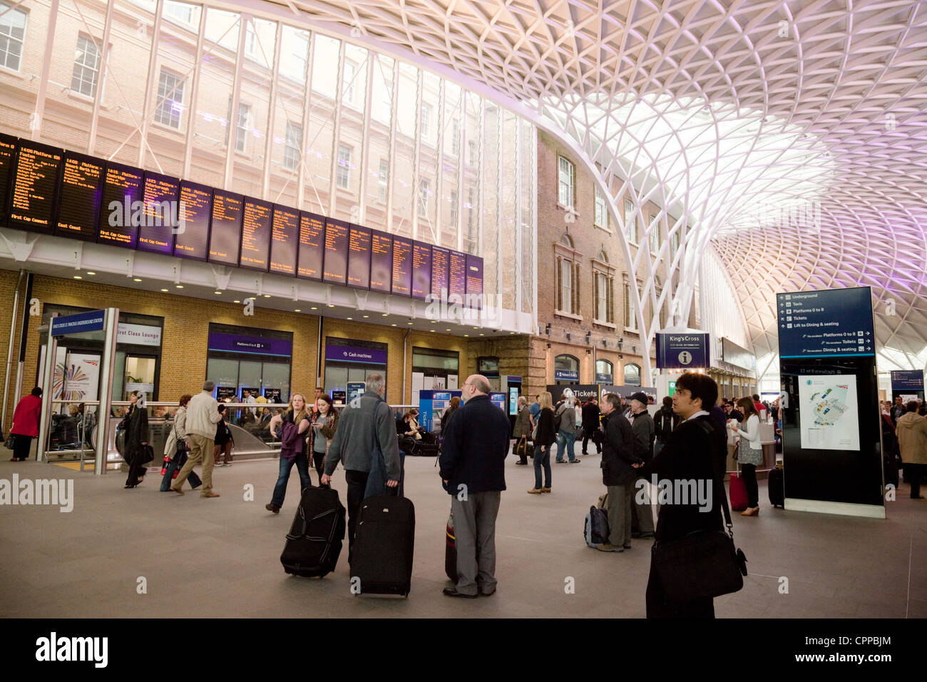 Persone che guardano la partenza di bordo sul piazzale di stazione Kings Cross, London REGNO UNITO Foto Stock