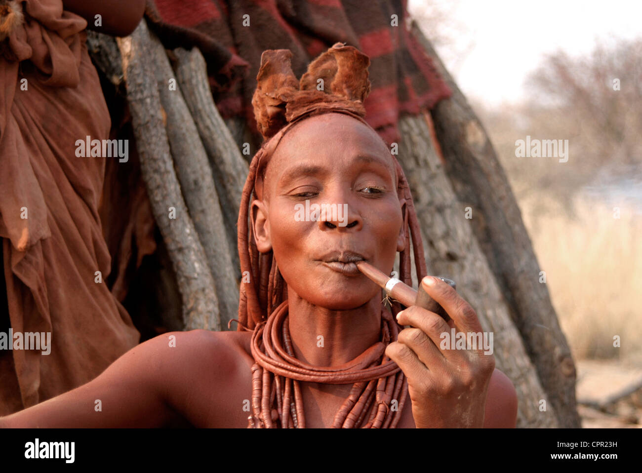 Gli Himba Matriach si siede e si gode il suo tubo. Foto Stock