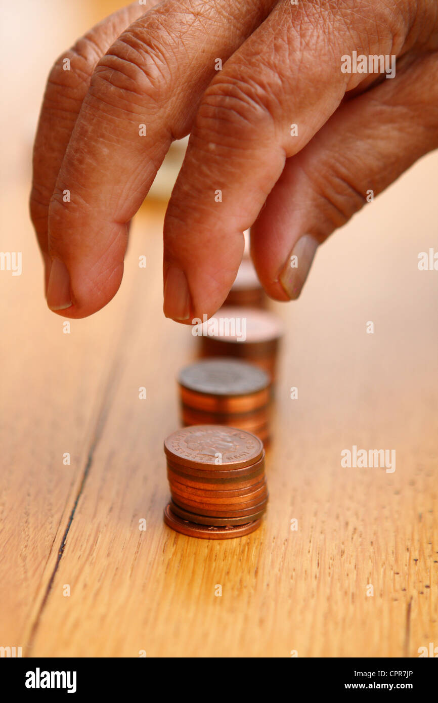 Sterling 2p di monete che vengono ordinati in piccole pile da una persona anziana Foto Stock