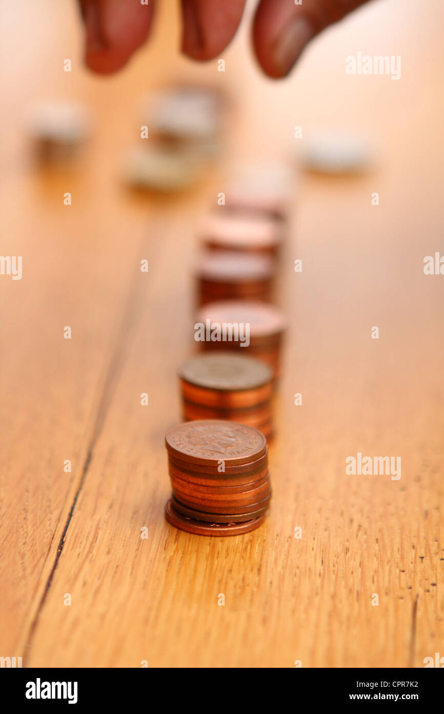 Sterling 2p di monete che vengono ordinati in piccole pile da una persona anziana e le cui dita sono solo visibili Foto Stock