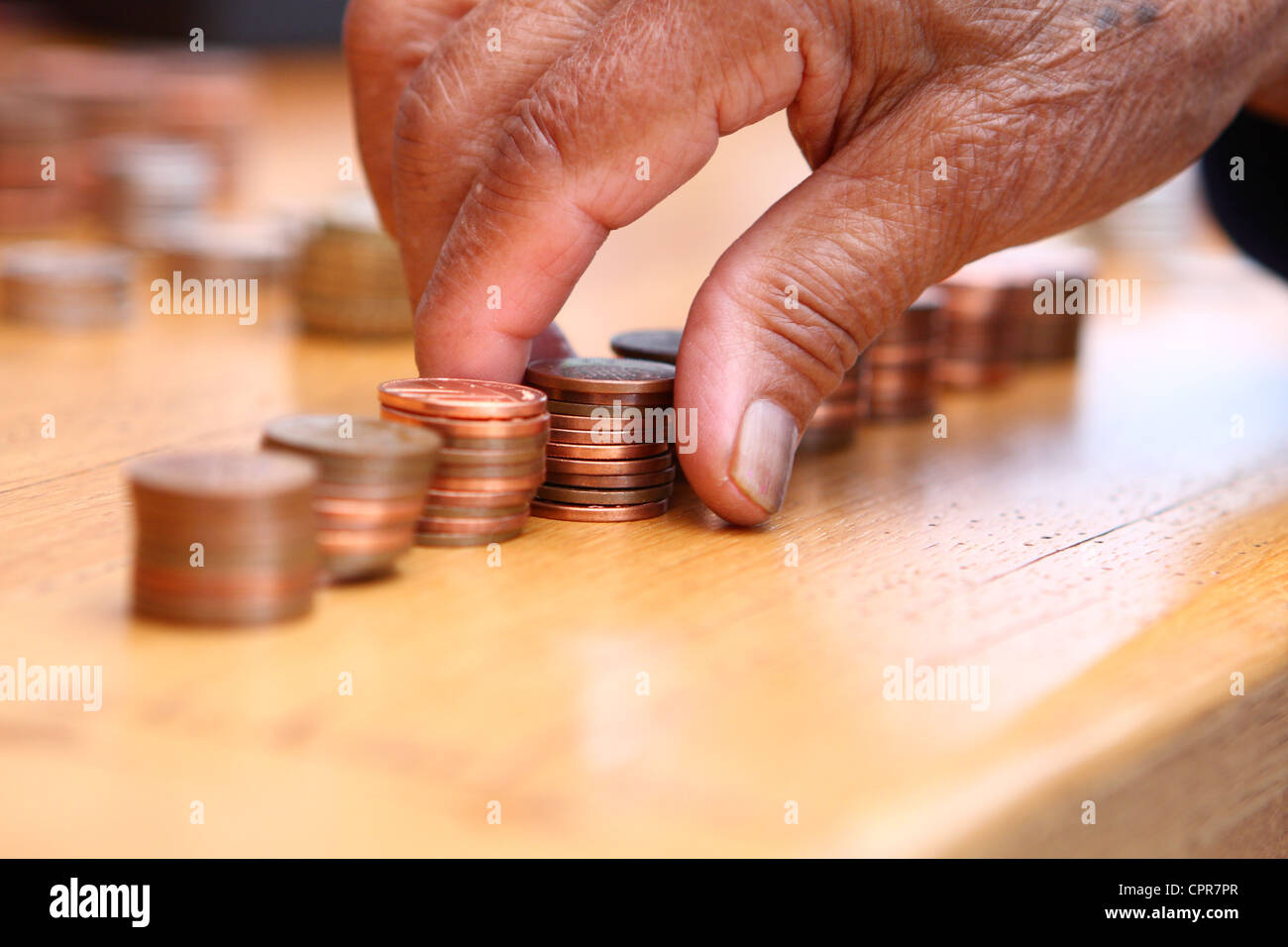 Sterling 2p di monete che vengono ordinati in piccole pile da una persona anziana Foto Stock