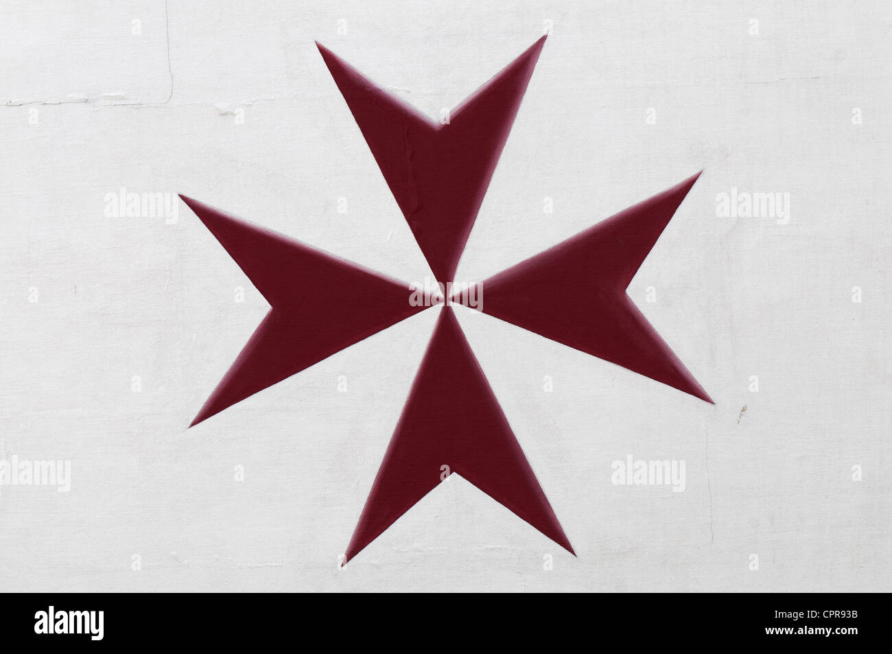 Rosso Maltese Cross dipinto sul muro bianco. Foto Stock