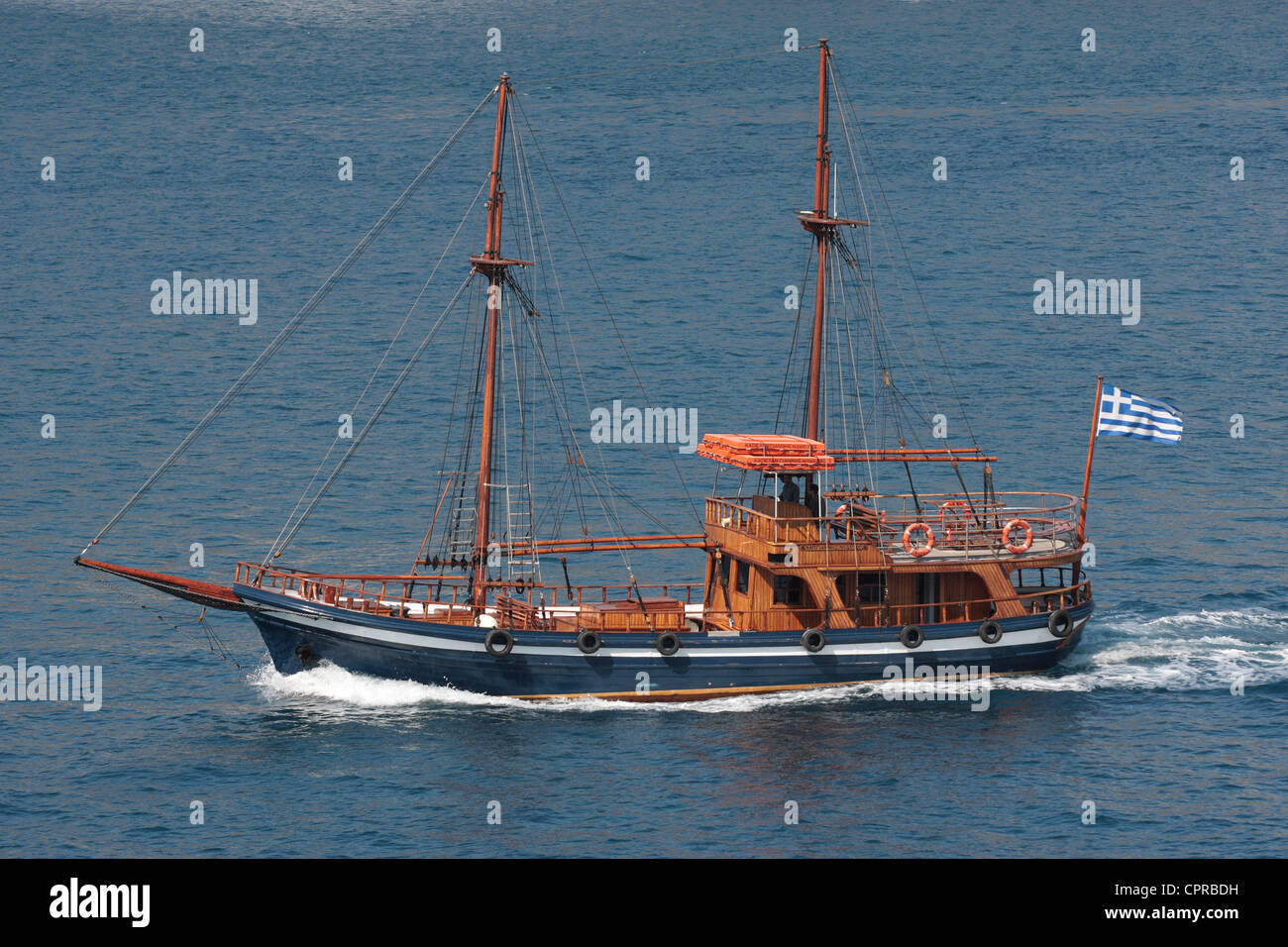 Una imbarcazione turistica truccate come una goletta ma senza vele, sotto potenza nella caldera di Santorini Foto Stock