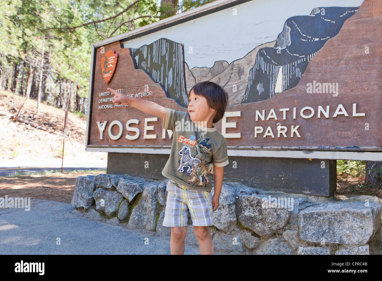 Un piccolo ragazzo asiatico in piedi nella parte anteriore del Parco Nazionale di Yosemite segno Foto Stock