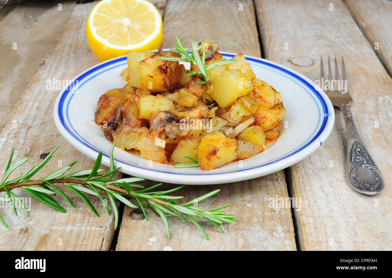 Patate arrosto e rosmarino in stile country su sfondo di legno Foto Stock