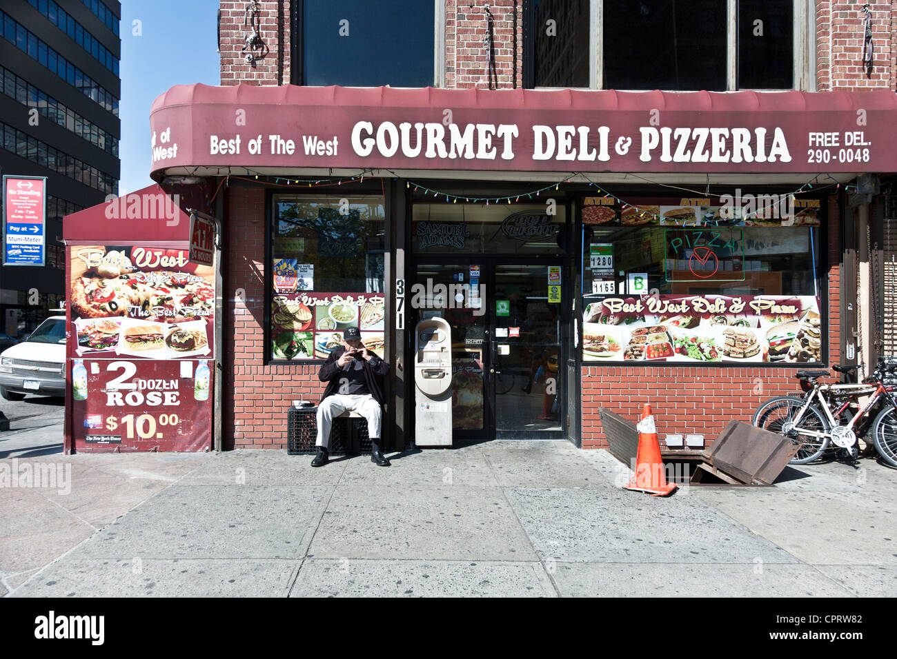 Vecchio ragazzo seduto su una cassa fuori tipica New York Deli Corner sulla bella giornata di fumare & parlando sul suo cellulare Manhattan Foto Stock