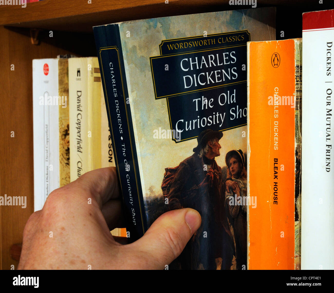 Una mano tenendo Charles Dickens il vecchio negozio di curiosità da uno scaffale Foto Stock