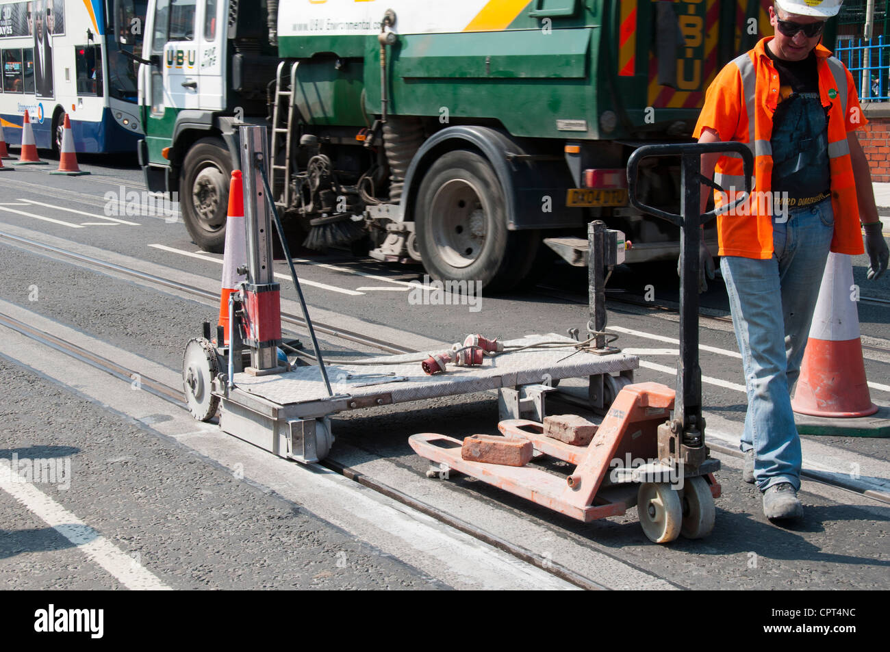 Macchina per la molatura di calcestruzzo lungo il bordo di nuova posa rotaie del tram. Manchester Rd, Droylsden, Manchester, Inghilterra, Regno Unito Foto Stock
