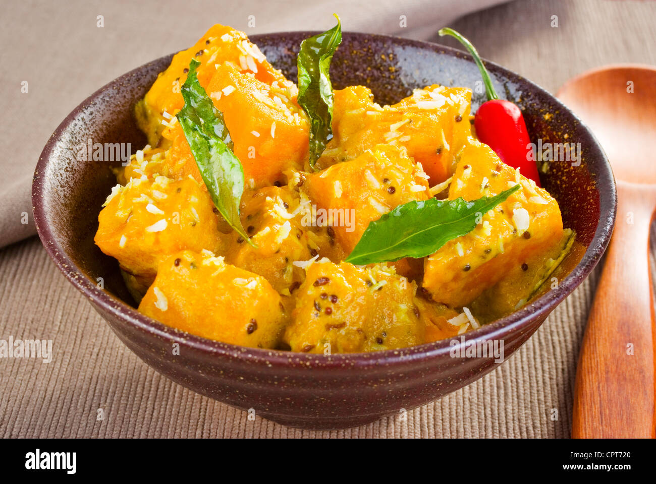 Una ciotola di chunky curry di zucca, aromatizzato con noce di cocco, di semi di senape, il cumino, il peperoncino e foglie di curry. Foto Stock