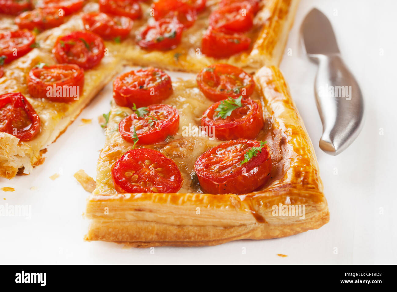 Crostata di pomodoro, pasta sfoglia guarnita con la senape, formaggio e ciliegia toamtoes. Foto Stock