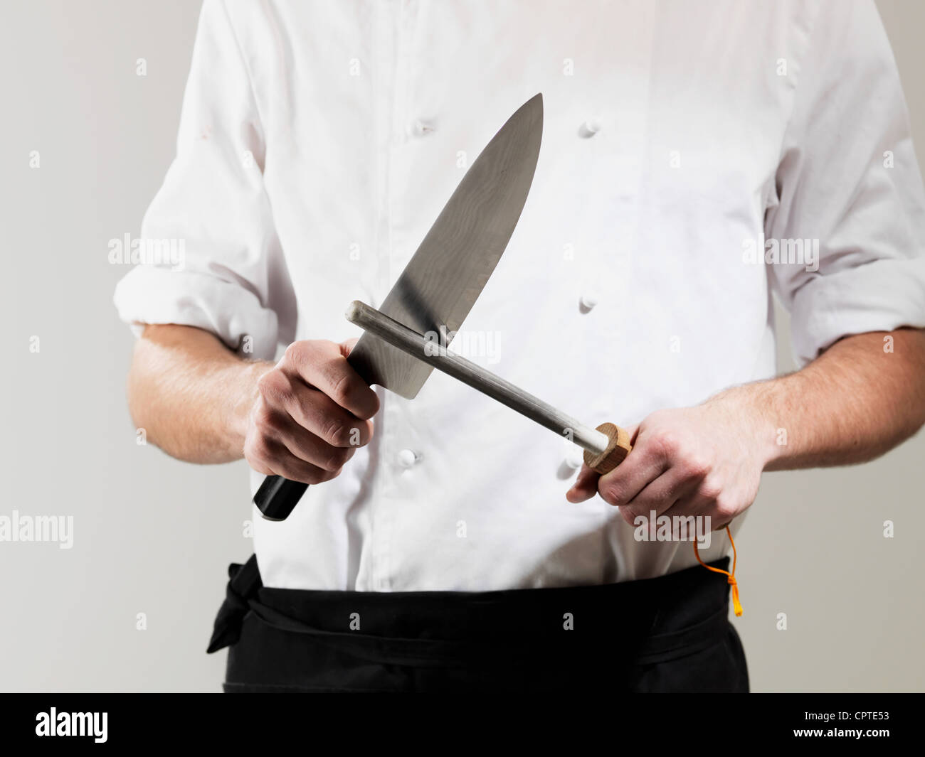 Lo Chef Affilare coltello contro uno sfondo bianco Foto Stock